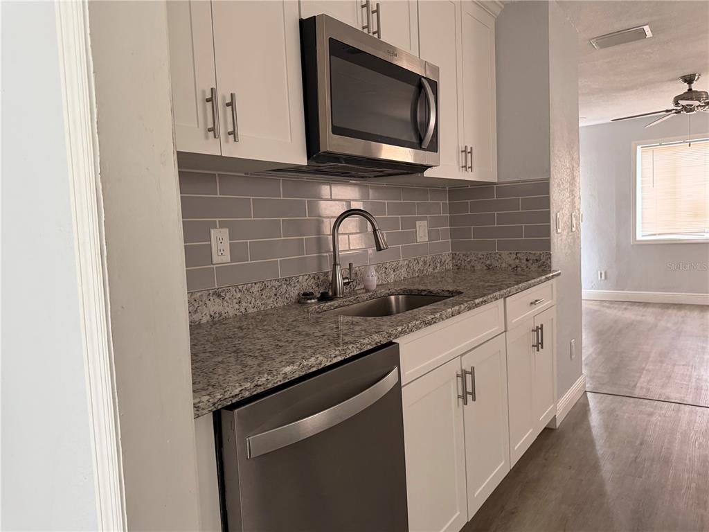 A kitchen features white cabinets, granite countertops, a stainless steel dishwasher, and gray subway tile — 4735 21ST AVENUE N, ST PETERSBURG, FL