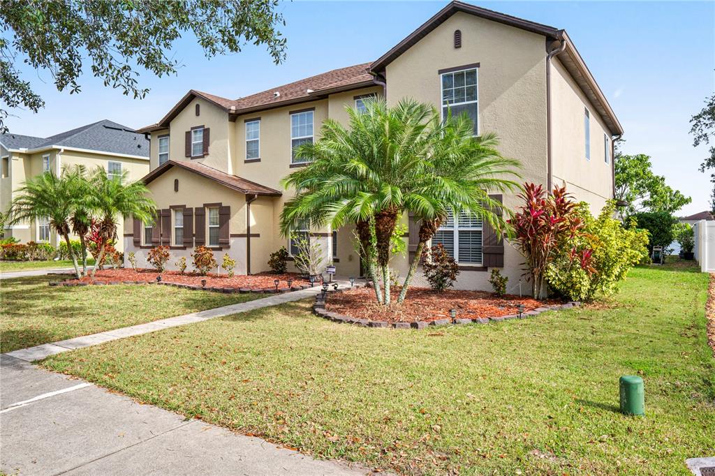 A two-story beige house with a palm tree in the front yard and brown shutters — 4071 FLOWERING PEACH LANE, ST CLOUD, FL