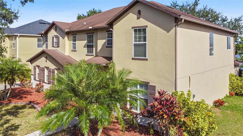A two-story tan stucco house with a brown shingled roof and a front palm tree — 4071 FLOWERING PEACH LANE, ST CLOUD, FL