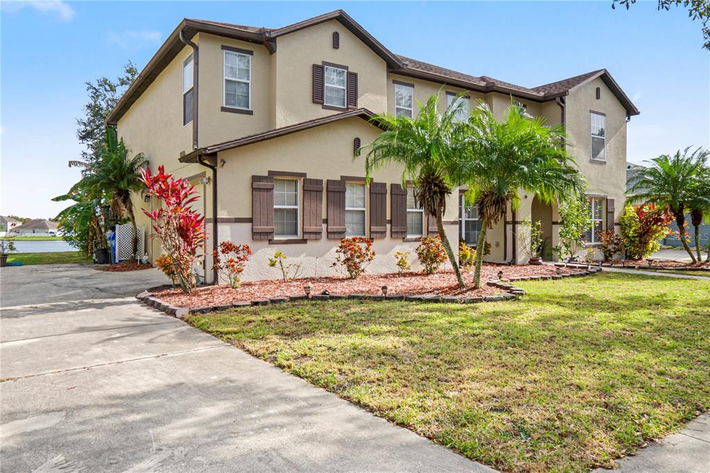 A two-story tan stucco house with brown shutters, a concrete driveway, and palm trees — 4071 FLOWERING PEACH LANE, ST CLOUD, FL