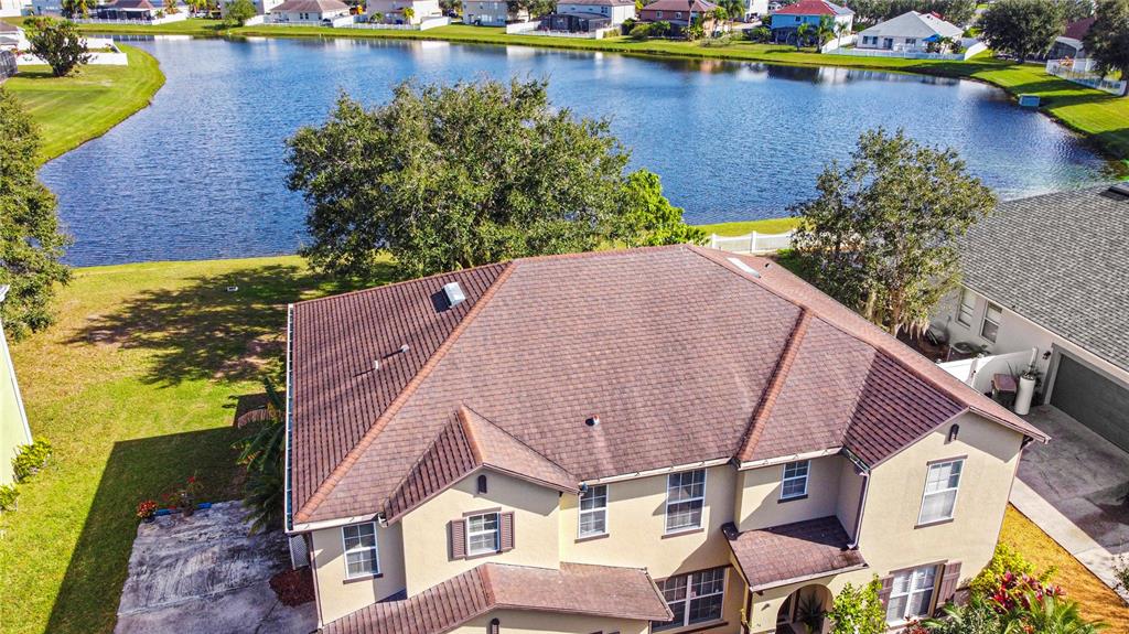 An aerial view of a two-story house with a brown shingled roof near a lake — 4071 FLOWERING PEACH LANE, ST CLOUD, FL
