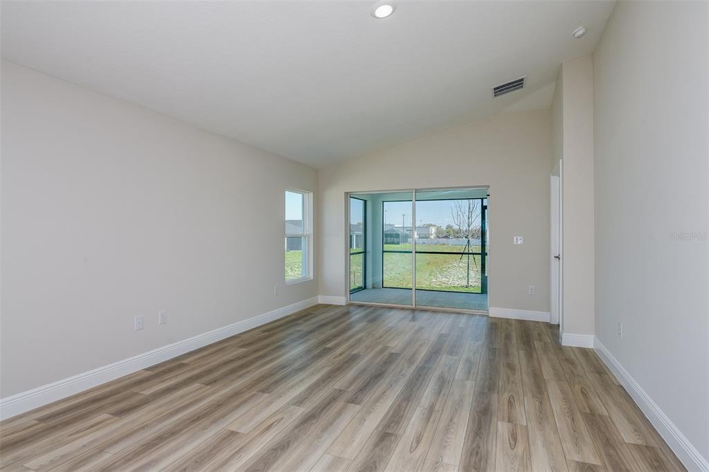 An empty room with light-colored walls, wood-look flooring, and sliding glass doors to a patio — 6085 SW 96TH PLACE, OCALA, FL