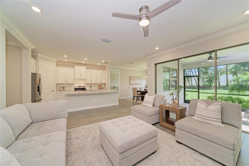An open-concept living room and kitchen featuring light-colored furniture, tile flooring, and a sliding door — 288 SOLIERA STREET, NOKOMIS, FL