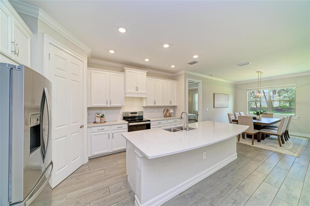 A modern kitchen features white cabinetry, a large quartz island, and light wood-look tile flooring — 288 SOLIERA STREET, NOKOMIS, FL