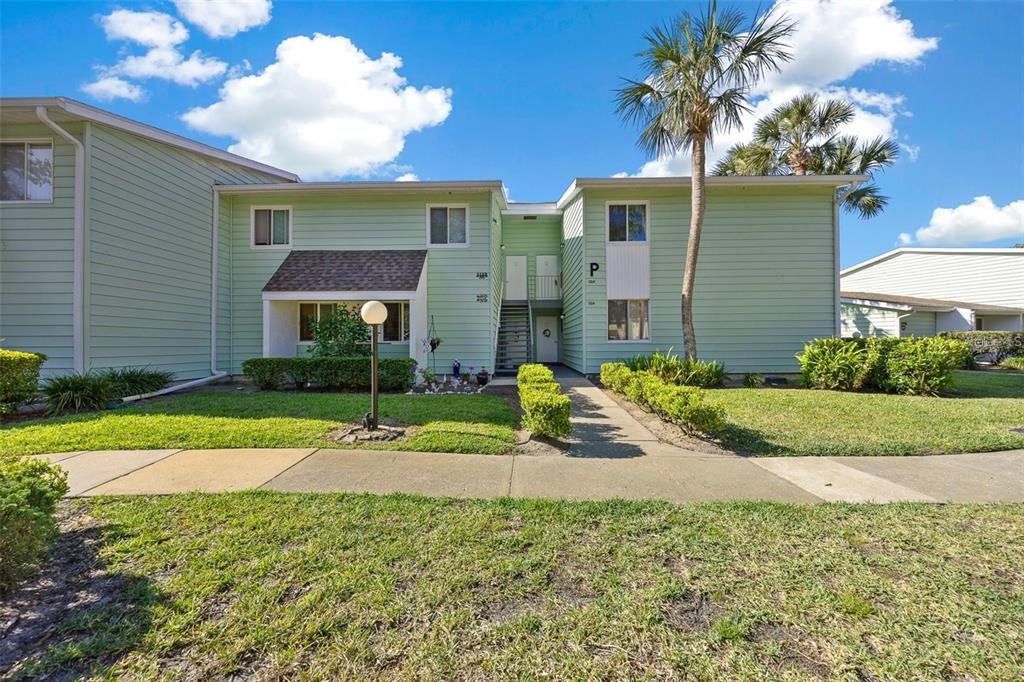 A two-story light green apartment building with a central staircase and a palm tree — 515 MIDWAY DRIVE UNIT A, OCALA, FL