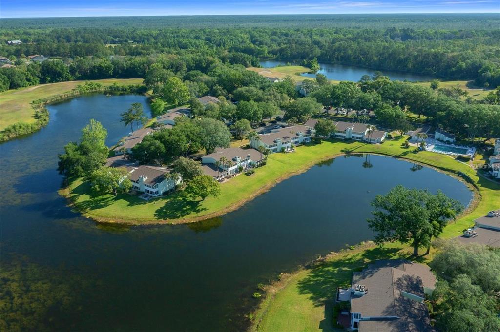 An aerial view shows multi-story residential buildings situated on a peninsula surrounded by a lake — 515 MIDWAY DRIVE UNIT A, OCALA, FL