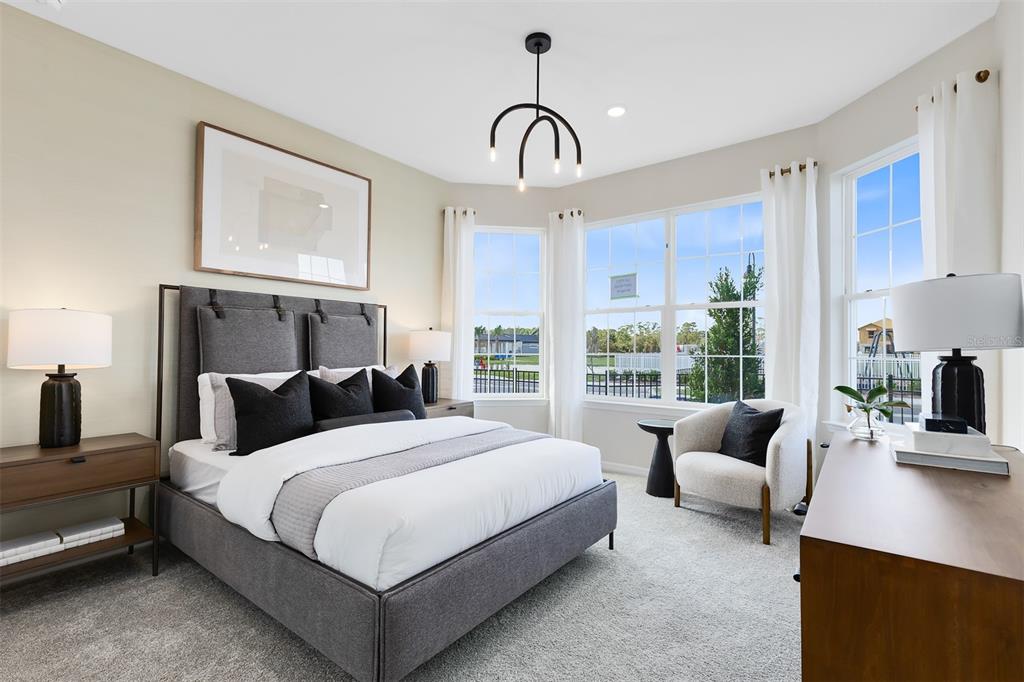 A bedroom features a gray upholstered bed, a corner armchair, and large windows with curtains — 5679 FLAME VINE WAY, ST CLOUD, FL