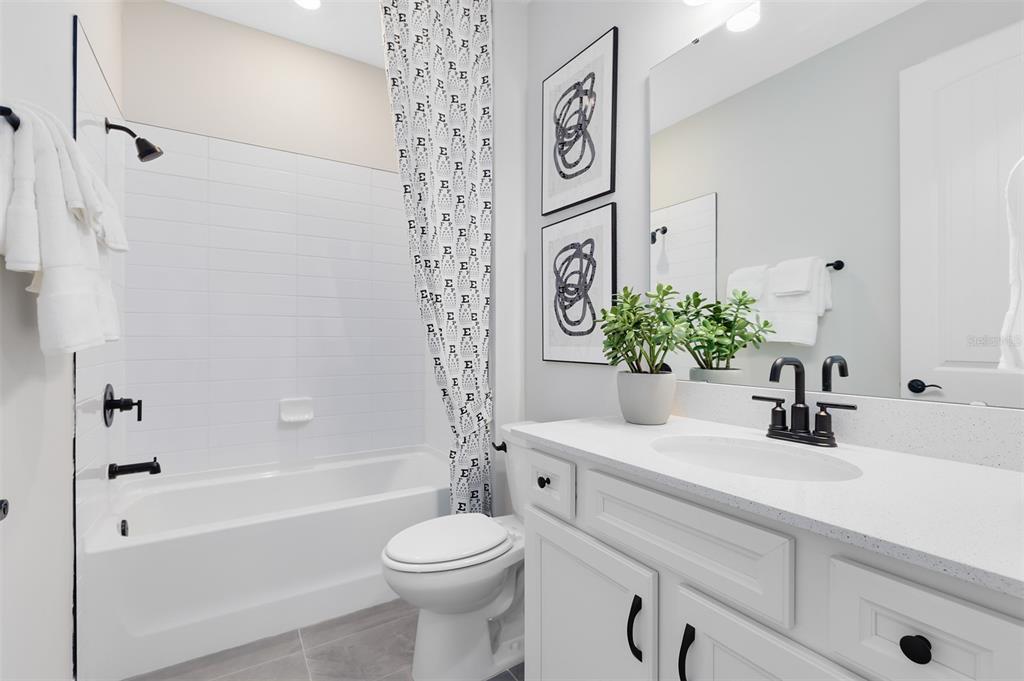 A bathroom features a white vanity, a tub-shower combination, and black fixtures — 5679 FLAME VINE WAY, ST CLOUD, FL