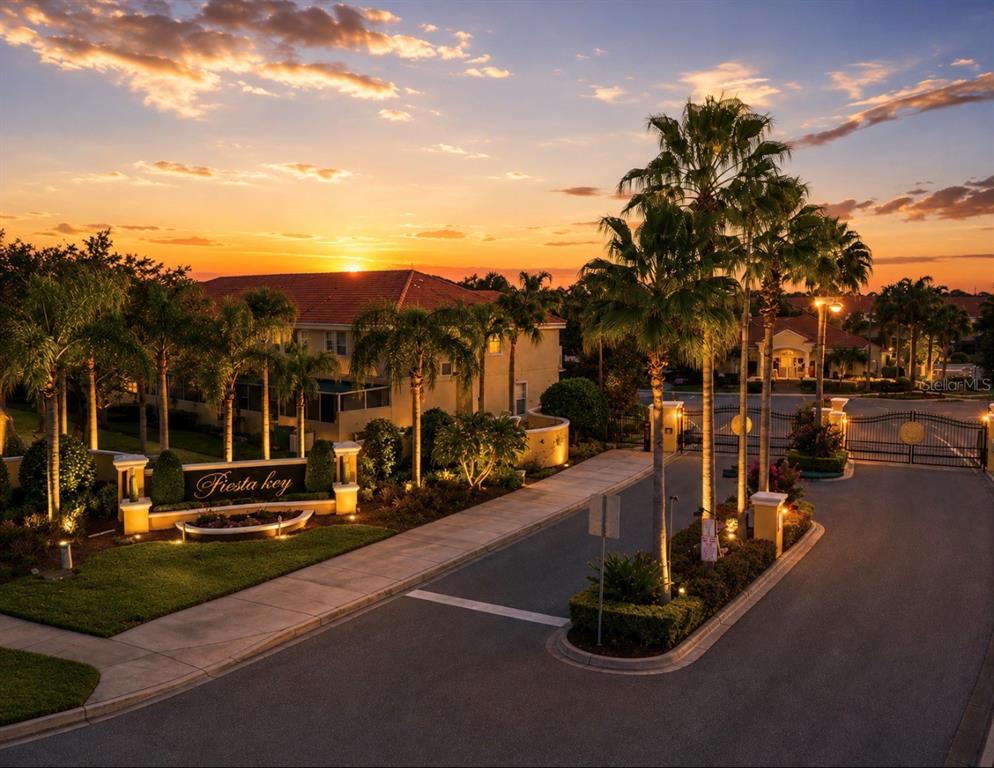 The entrance to the Fiesta Key community features a sign, palm trees, and a gated road — 4814 CORAL CASTLE DRIVE, KISSIMMEE, FL