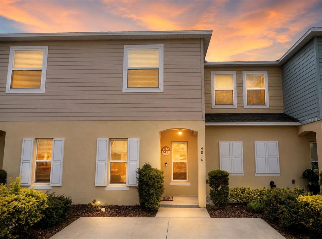 The exterior of a two-story townhouse features tan siding, stucco walls, and a concrete walkway — 4814 CORAL CASTLE DRIVE, KISSIMMEE, FL