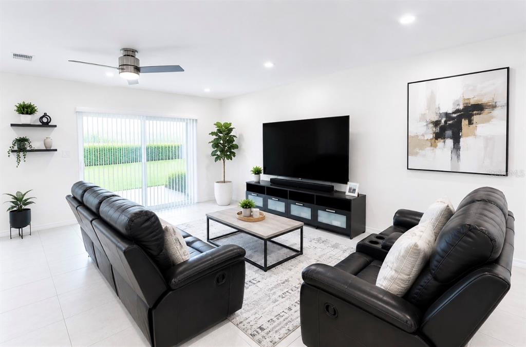 A living room features two black leather sofas, a television on a stand, and tile flooring — 4814 CORAL CASTLE DRIVE, KISSIMMEE, FL
