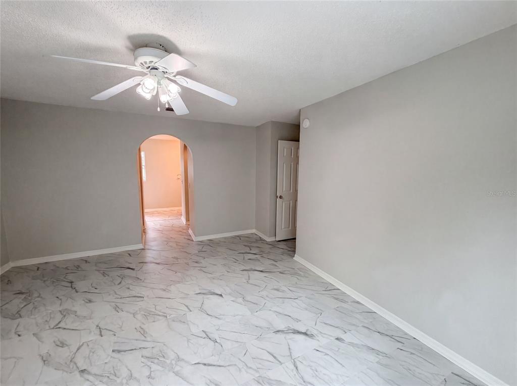An empty room with light gray walls, white marble-patterned tile floors, and a ceiling fan — 5191 QUINTILIS STREET, SPRING HILL, FL