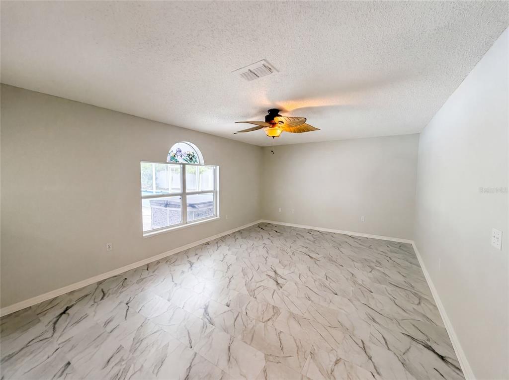 A dining area features white marble-look tile flooring, arched wall cutouts, and sliding glass patio doors — 5191 QUINTILIS STREET, SPRING HILL, FL