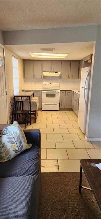 A kitchen with light gray cabinets, white appliances, and tiled floors viewed from a living area — 5004 AVERY ROAD, NEW PORT RICHEY, FL