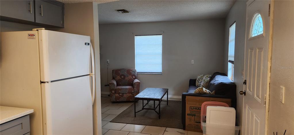 A kitchen with a white refrigerator opens into a living area featuring a sofa and chair — 5004 AVERY ROAD, NEW PORT RICHEY, FL