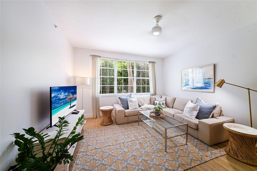 A living room features a beige sectional sofa, a glass coffee table, and a television — 3506 54TH DRIVE W UNIT 106, BRADENTON, FL