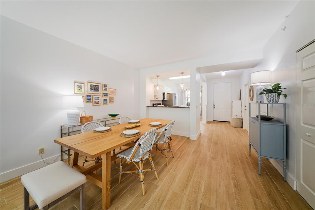A dining room with a wooden table, woven chairs, and a view into the kitchen — 3506 54TH DRIVE W UNIT 106, BRADENTON, FL