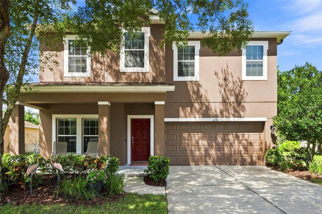 A two-story house with a brown stucco exterior, a red front door, and a two-car garage — 11245 BELLE HAVEN DRIVE, NEW PORT RICHEY, FL