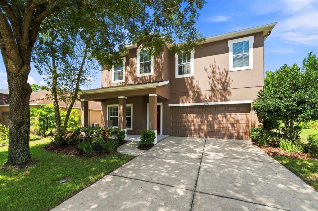A two-story brown house with a concrete driveway, a front porch, and a two-car garage — 11245 BELLE HAVEN DRIVE, NEW PORT RICHEY, FL