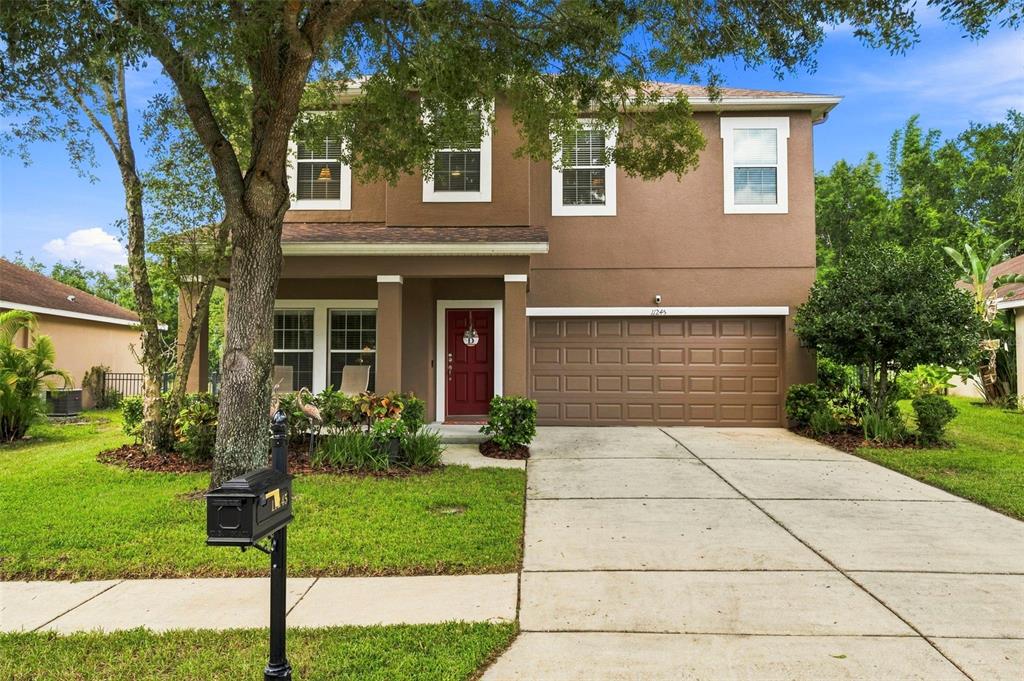 A two-story brown house with a red front door, a garage, and a front lawn — 11245 BELLE HAVEN DRIVE, NEW PORT RICHEY, FL