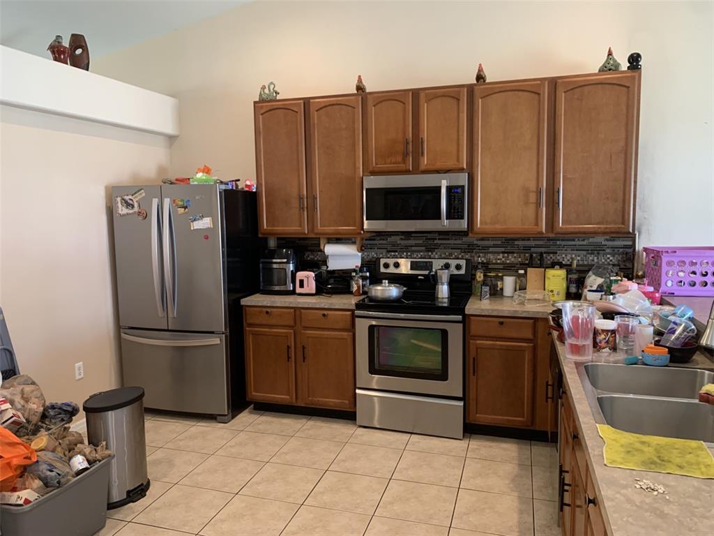 A kitchen island with a double sink overlooks a living room with a sliding glass door — 1734 MINNOW COURT, POINCIANA, FL