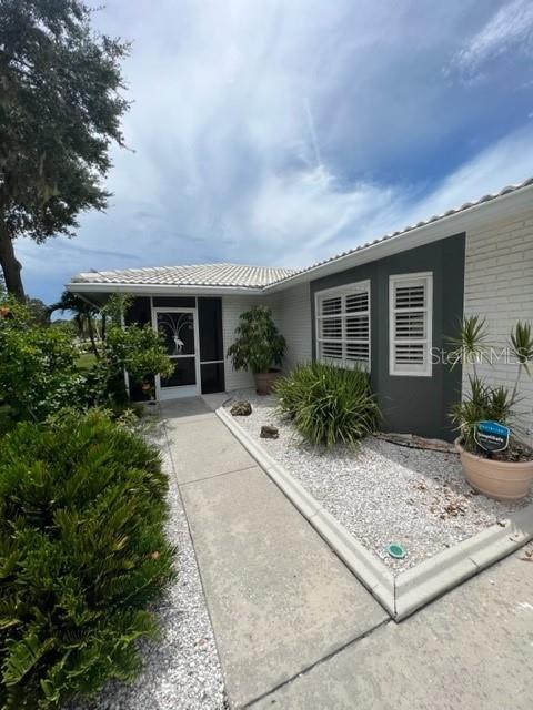 A concrete walkway leads to the front entrance of a house with white brick siding — 7328 CURTISS AVENUE, SARASOTA, FL