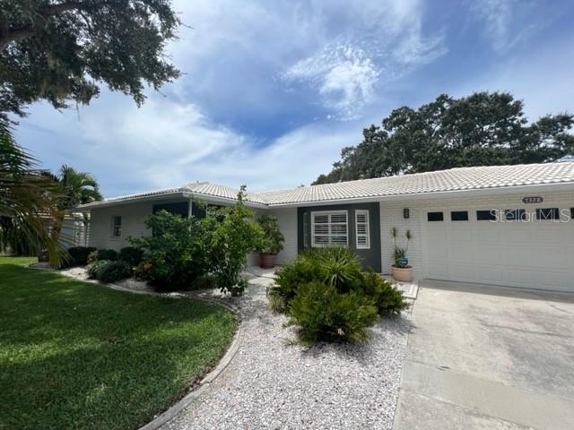 A single-story house with a white brick exterior, a tiled roof, and a concrete driveway — 7328 CURTISS AVENUE, SARASOTA, FL