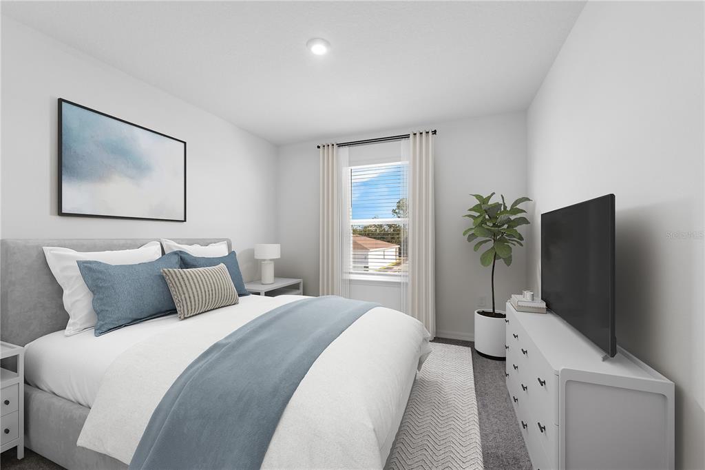 A bedroom features a gray upholstered bed, a white dresser with a television, and a window — 6036 CLIFFBOW LOOP, LEESBURG, FL