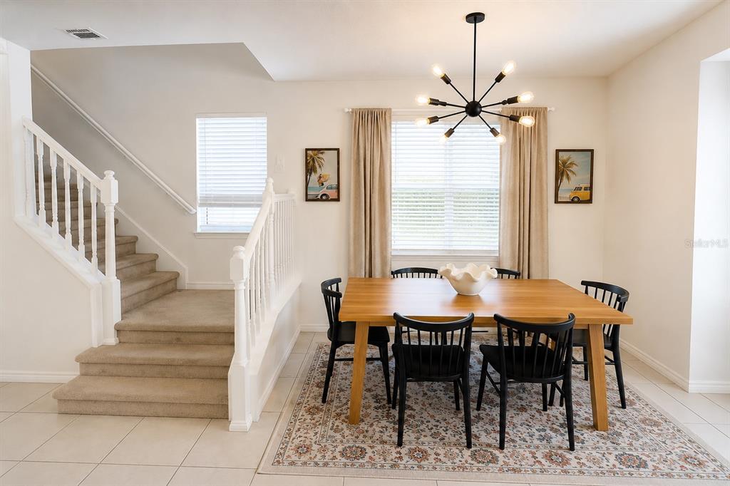 A dining area with a wooden table, black chairs, and a staircase to the left — 2441 DUBAI STREET, KISSIMMEE, FL