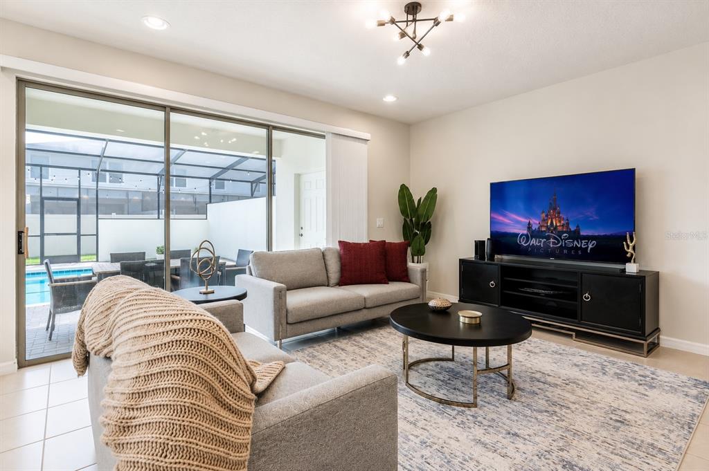 A living room features two gray sofas, a round coffee table, and a large television — 2441 DUBAI STREET, KISSIMMEE, FL