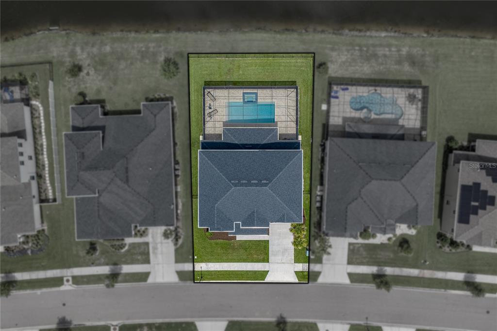 An aerial view shows a house with a screened-in pool and backyard facing a lake — 6978 BRADBURY CIRCLE, WESLEY CHAPEL, FL