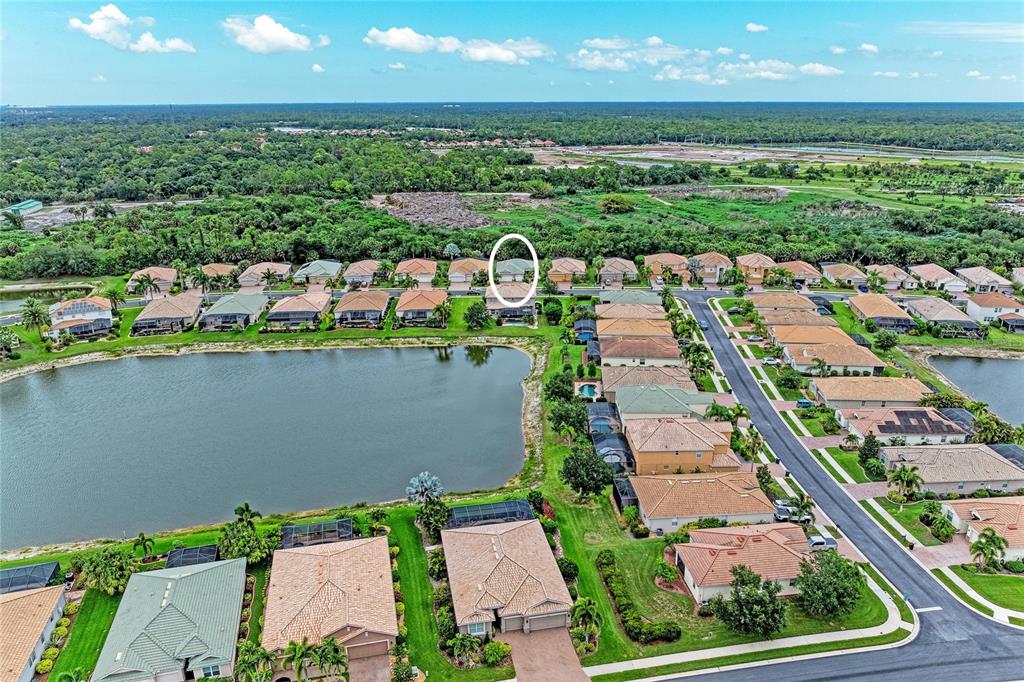 An aerial view shows a suburban neighborhood with houses surrounding a lake — 1986 MESIC HAMMOCK WAY, VENICE, FL