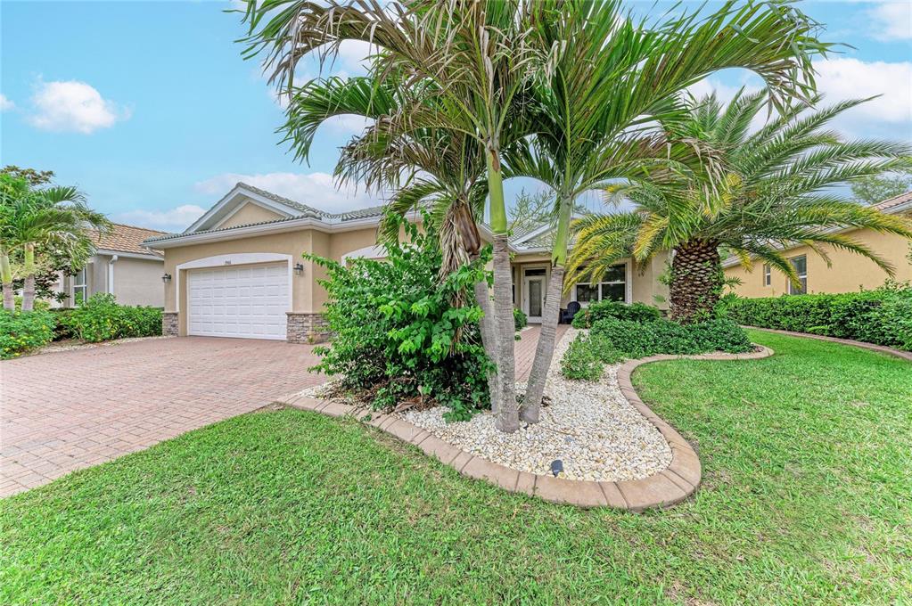 A single-story house with a paved driveway, a two-car garage, and palm trees in front — 1986 MESIC HAMMOCK WAY, VENICE, FL