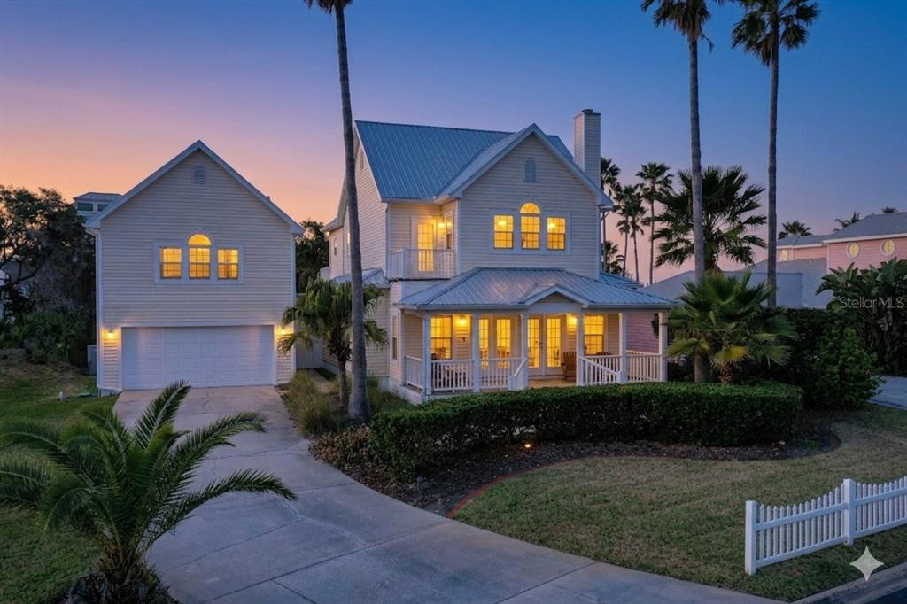 A two-story yellow house with a metal roof, front porch, and attached garage at dusk — 252 GULL CIRCLE, PONTE VEDRA, FL