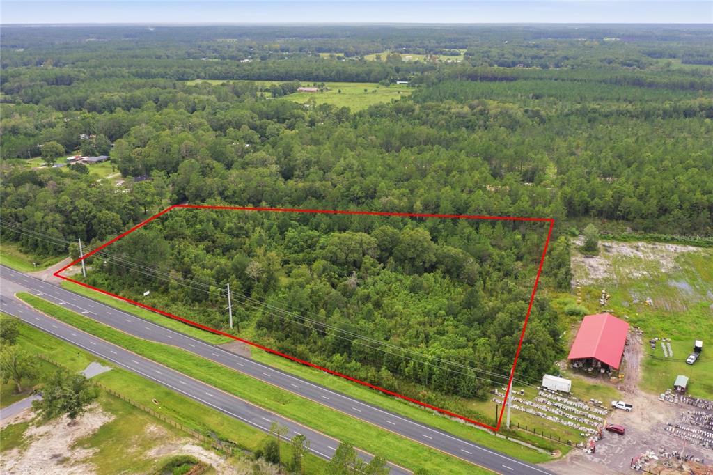 An aerial view shows a rural property with a red-roofed barn, wooded areas, and buildings — 19978 N HIGHWAY 301, STARKE, FL