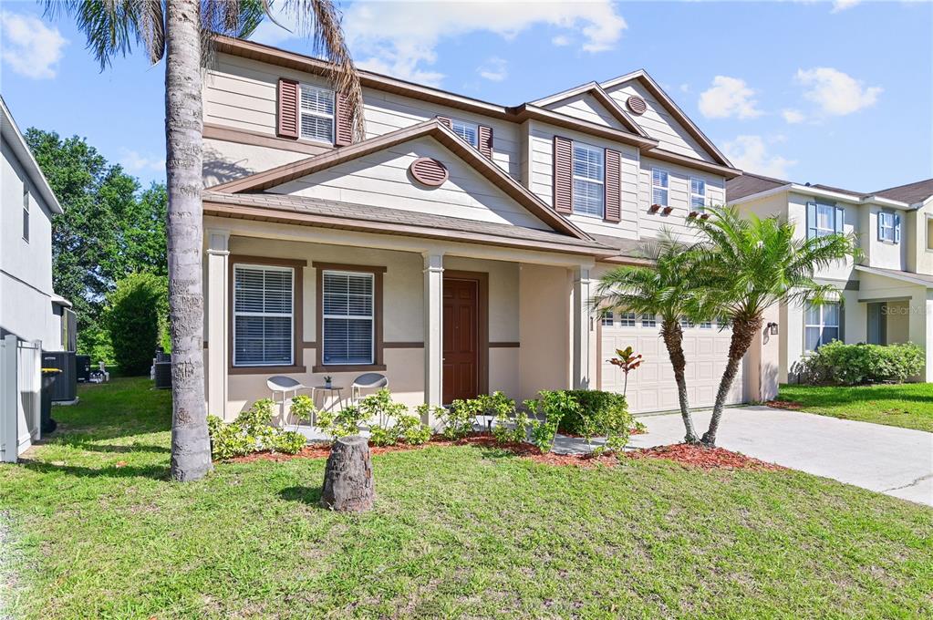 A two-story suburban house features a covered front porch, a garage, and a palm tree — 701 KETTERING ROAD, DAVENPORT, FL