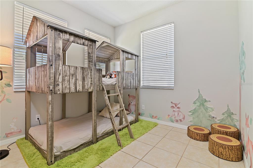 A child's bedroom features a rustic wooden bunk bed, green rug, and woodland-themed wall decals — 701 KETTERING ROAD, DAVENPORT, FL