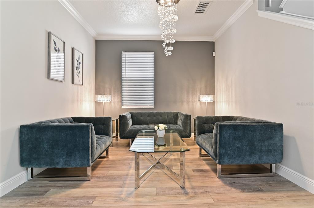 A formal living room features three dark blue velvet sofas, a glass coffee table, and chandelier — 701 KETTERING ROAD, DAVENPORT, FL