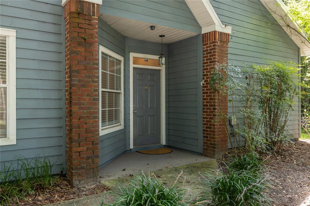 The exterior of a house features blue siding, brick columns, and a gray front door — 501 NW 50TH BOULEVARD, GAINESVILLE, FL