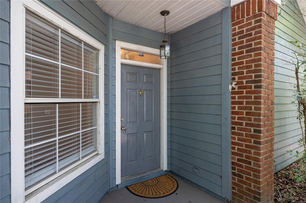 The exterior entrance features a gray door, a brick column, and a window with blinds — 501 NW 50TH BOULEVARD, GAINESVILLE, FL