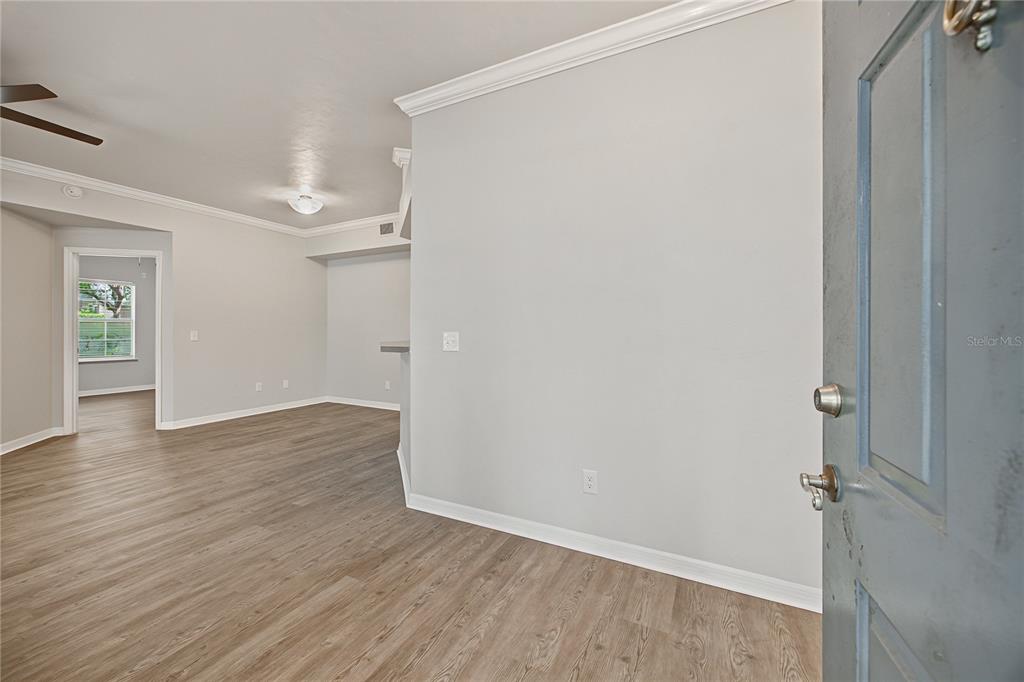 An interior view shows a light-walled room with wood-look flooring and an open doorway — 501 NW 50TH BOULEVARD, GAINESVILLE, FL