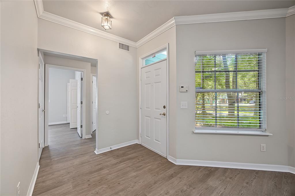 An entryway with light wood-look flooring, a white front door, and a window with blinds — 501 NW 50TH BOULEVARD, GAINESVILLE, FL