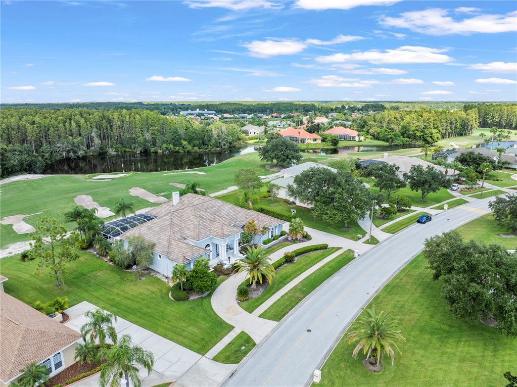 An aerial view shows a single-story house with a pool cage beside a golf course — 4529 CHEVAL BOULEVARD, LUTZ, FL