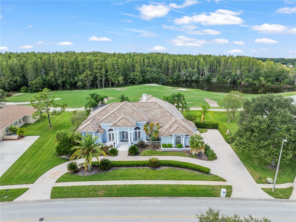 An aerial view shows a light blue house with a tiled roof facing a golf course — 4529 CHEVAL BOULEVARD, LUTZ, FL