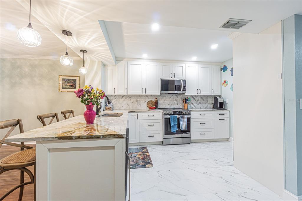 A living and dining room with wood-look flooring, blue furniture, and a round dining table — 3505 TARPON WOODS BOULEVARD UNIT G405, PALM HARBOR, FL