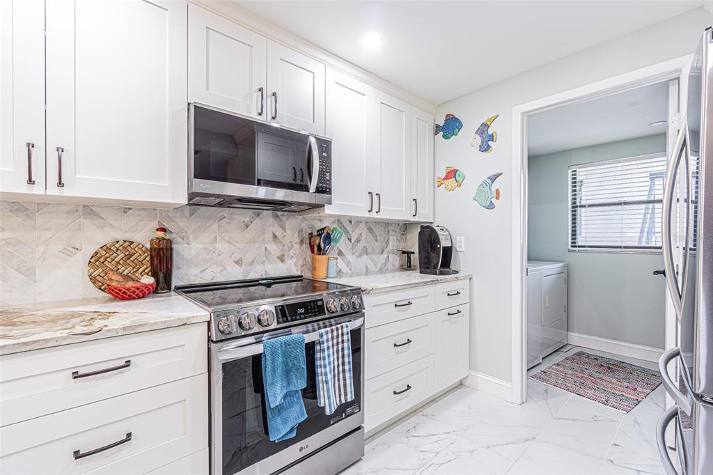 A modern kitchen with white cabinets, stainless steel appliances, and marble-look flooring — 3505 TARPON WOODS BOULEVARD UNIT G405, PALM HARBOR, FL