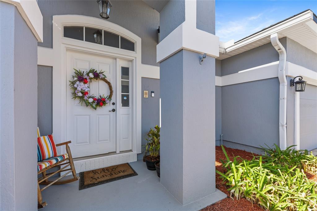 A front porch features a white door with a wreath, a rocking chair, and landscaping — 45095 DUTTON WAY, CALLAHAN, FL