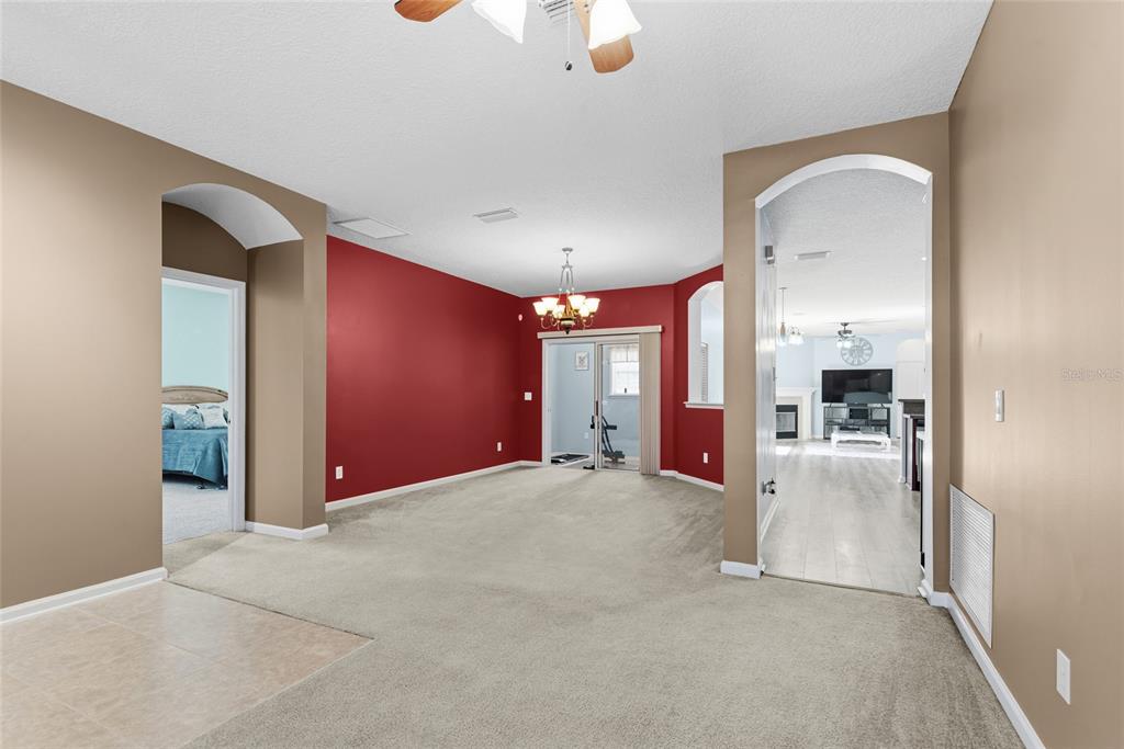 A carpeted living room features a red accent wall, a ceiling fan, and arched doorways — 45095 DUTTON WAY, CALLAHAN, FL
