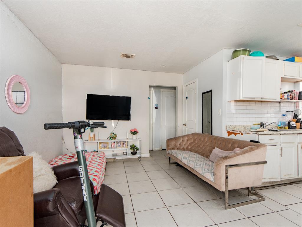 A living room with tile floors, a brown sofa, a television, and a scooter — 2532 W WALNUT STREET, TAMPA, FL