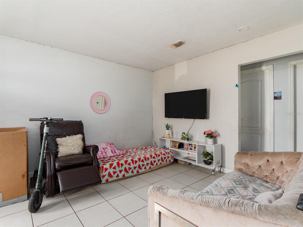A living room features a tiled floor, a wall-mounted television, a recliner, and a daybed — 2532 W WALNUT STREET, TAMPA, FL